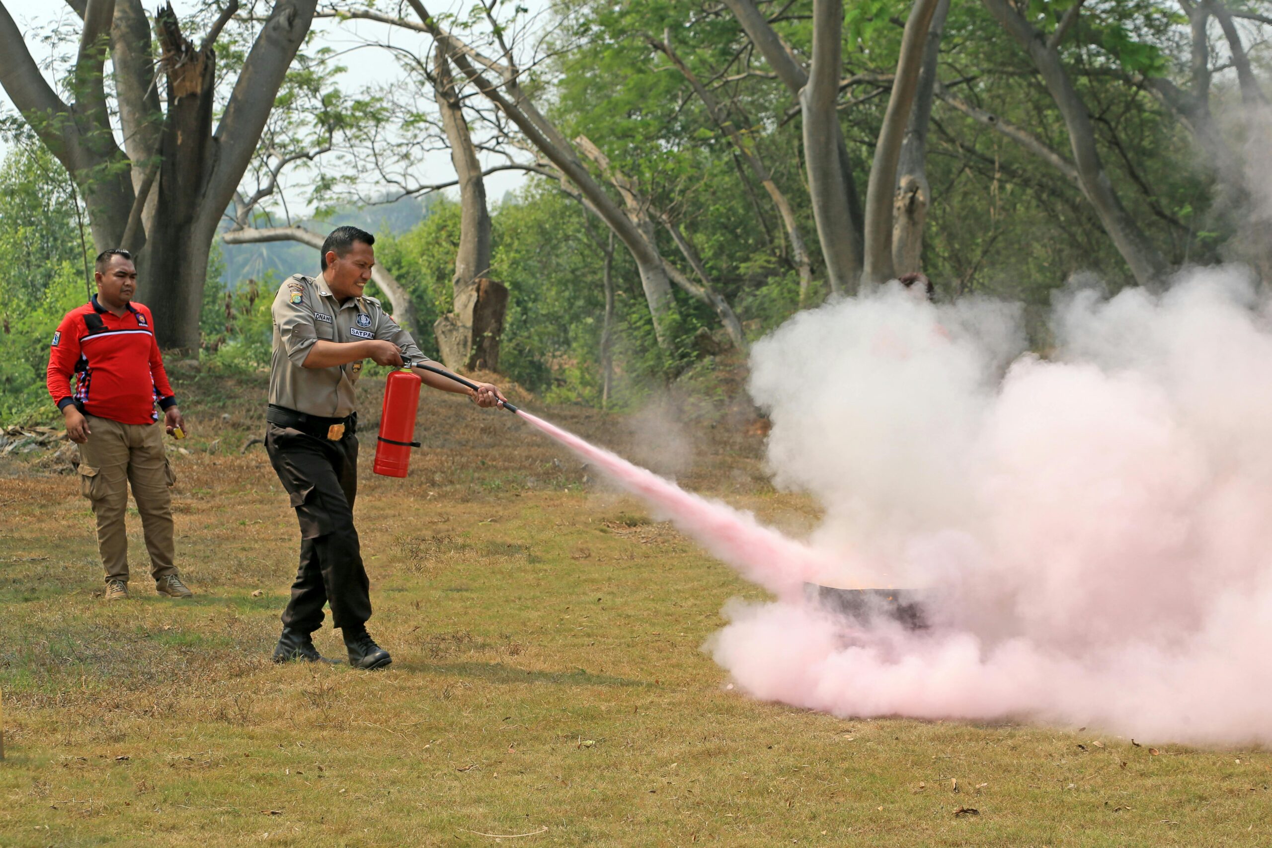 A fire safety officer demonstrates use of an extinguisher during outdoor training. Fire Safety Services Vadodara